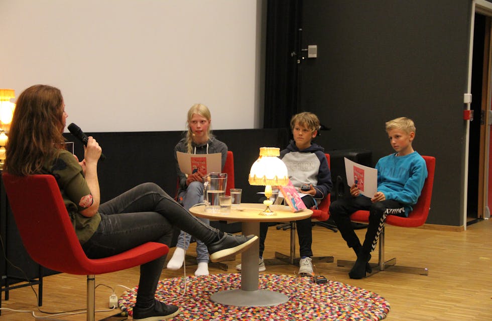 Forfattar Anne Audhild Solberg blir bokbada av 7. klassingane Sigrid Momb Hammersland, Unar Stenberg og David Øren. 
Foto: Grethe Hopland Ravn