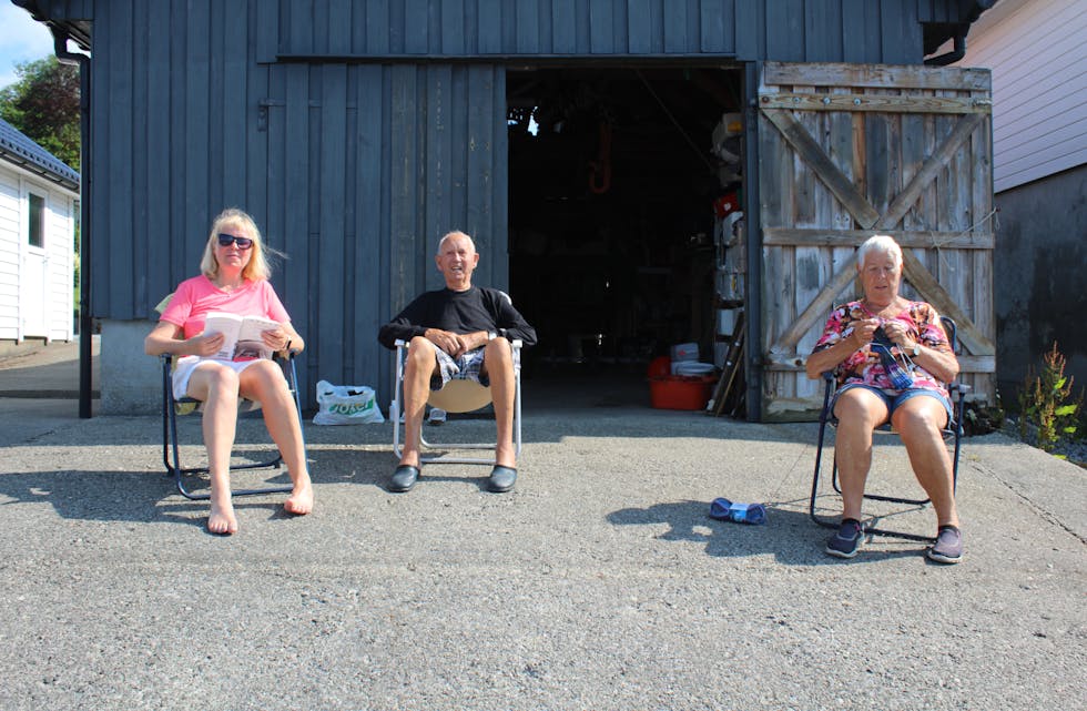 Wenche Nesse Gjesdal (55), Kåre Nesse (88) og Kirsten Nesse (87) nyt sola utanføre naustet deira i Vikebygd.